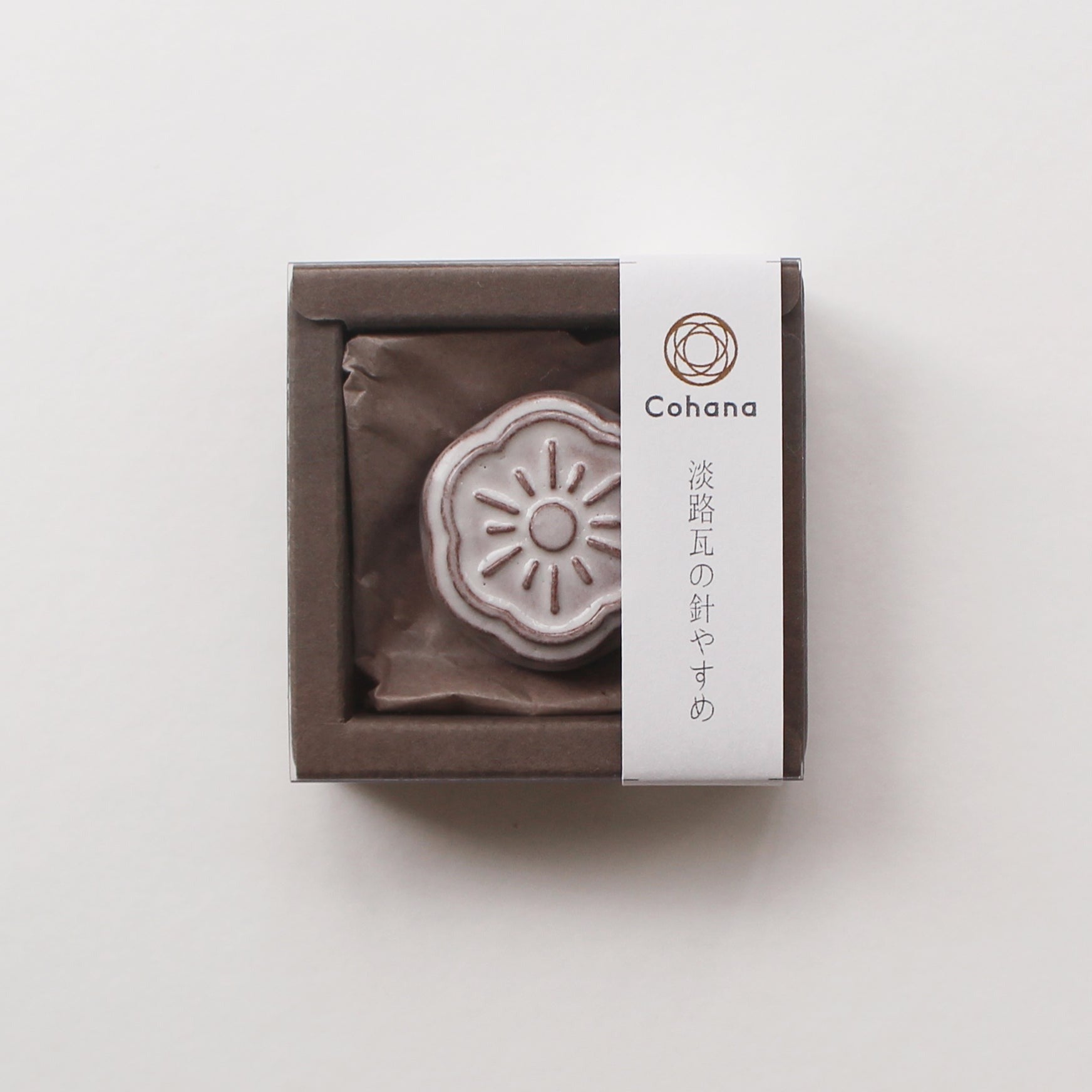 Small white ceramic needle rest by cohana in box on white background