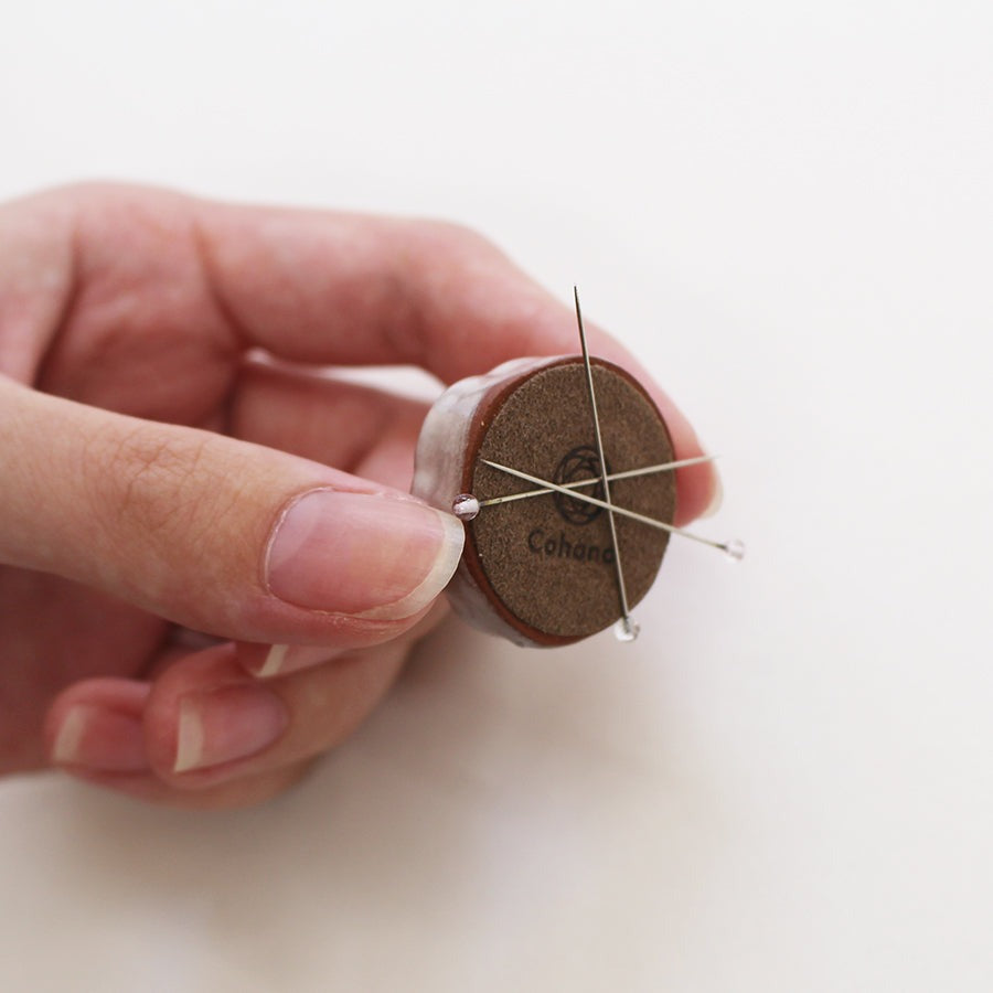 Hand holding ceramic needle rest with pins attached