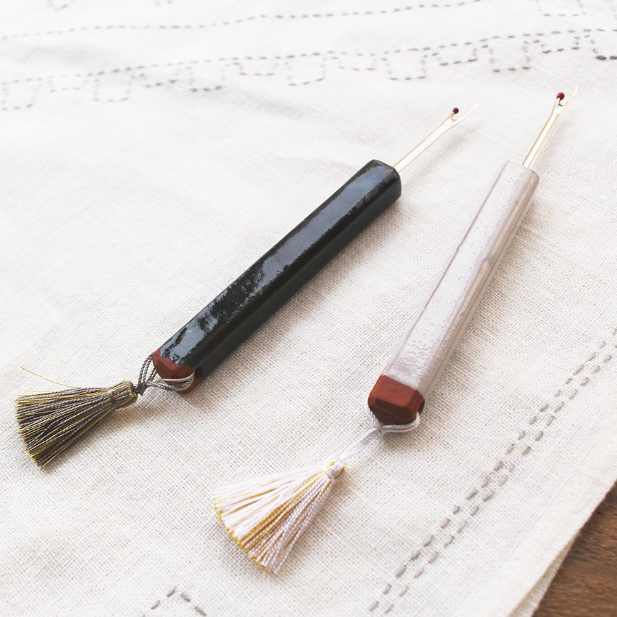 Dark grey and white ceramic handled seam rippers by cohana on top of white fabric