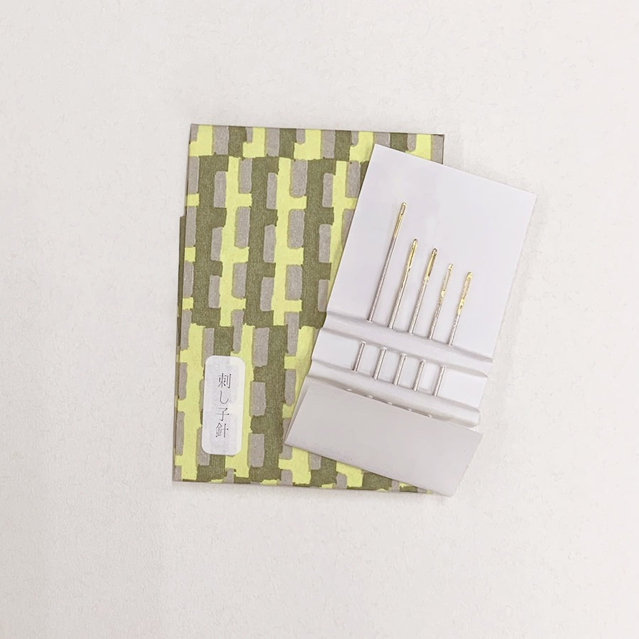 Cohana embroidery needles on top of light green and dark green patterned washi paper case