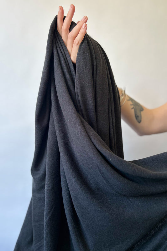 Hand holding Hemp and lyocell jersey knit fabric in black
