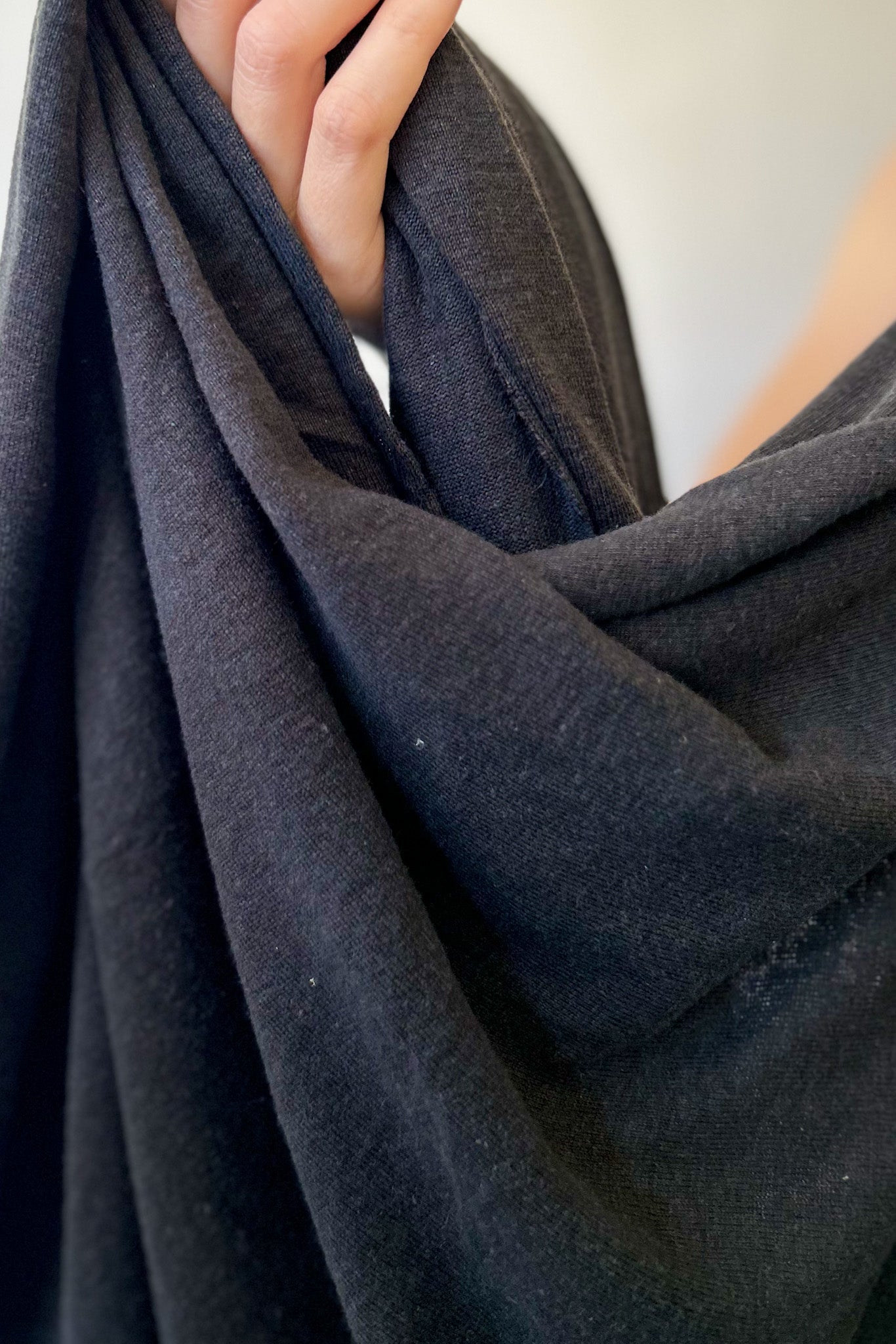 Close up of hand holding hemp and lyocell jersey knit fabric in black