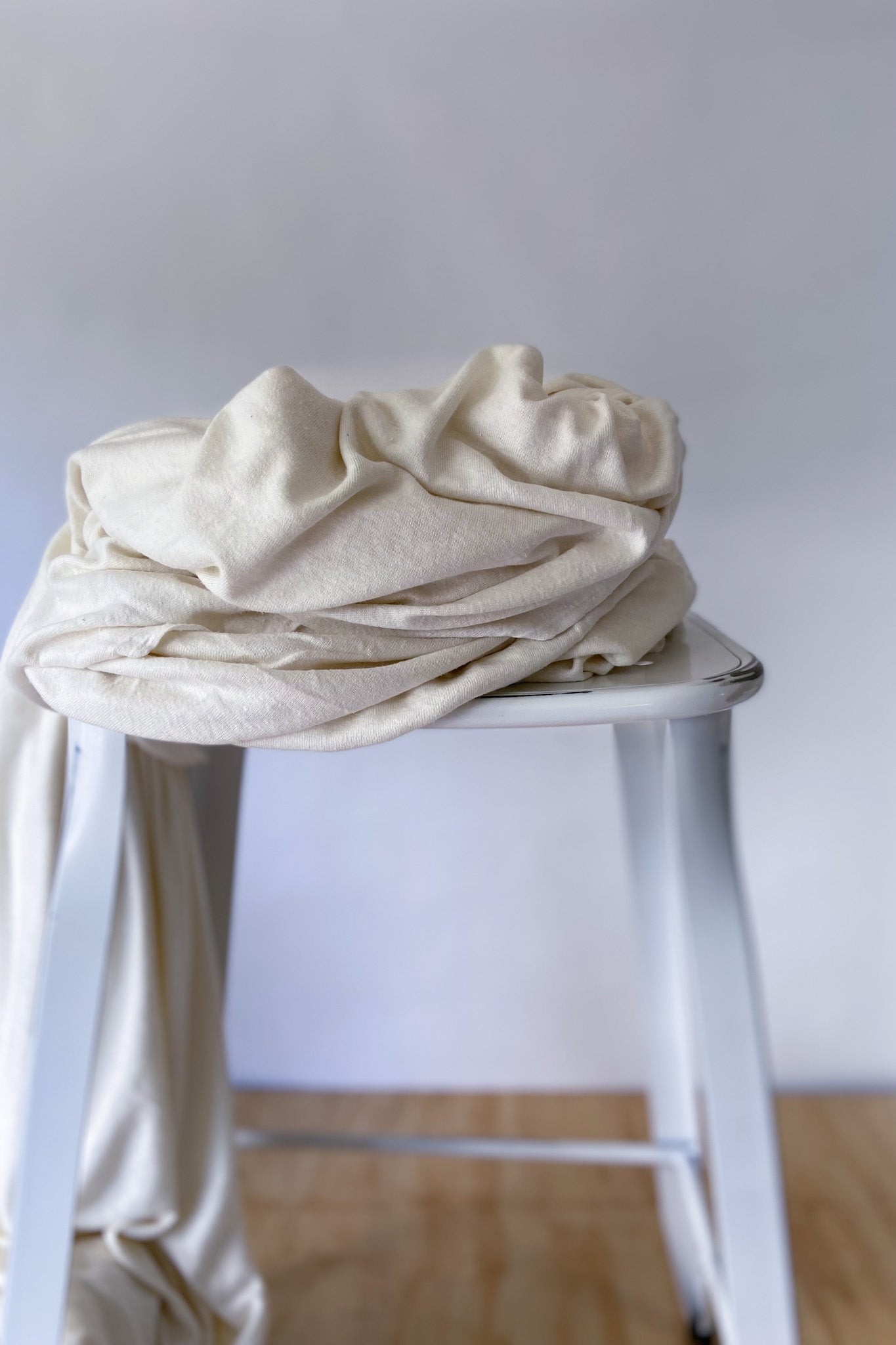 Cream coloured hemp and lyocell jersey knit fabric piled on white stool