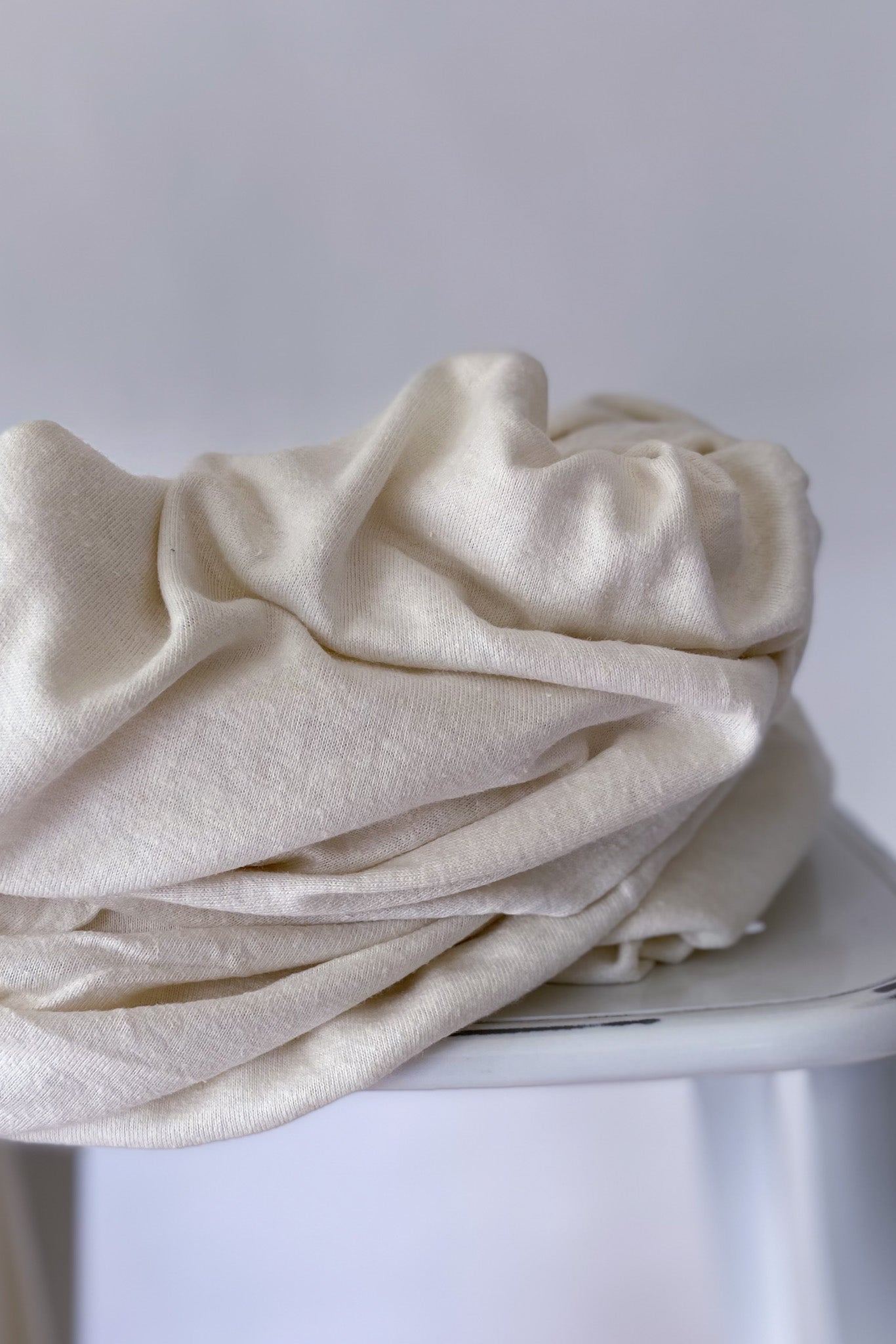 Natural white hemp and lyocell jersey fabric piled on white stool
