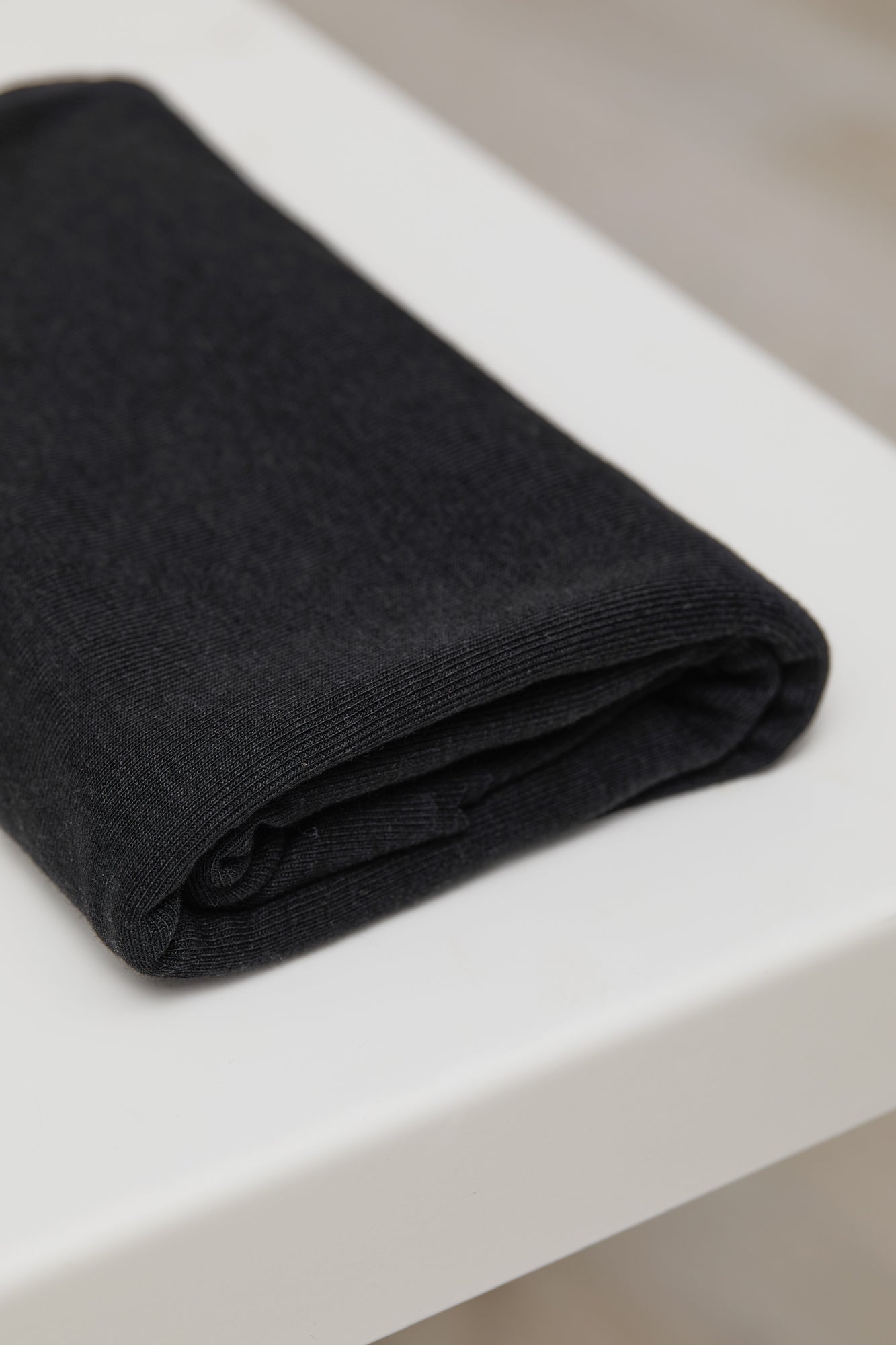 Black organic cotton and tencel knit sewing fabric folded on top of white table