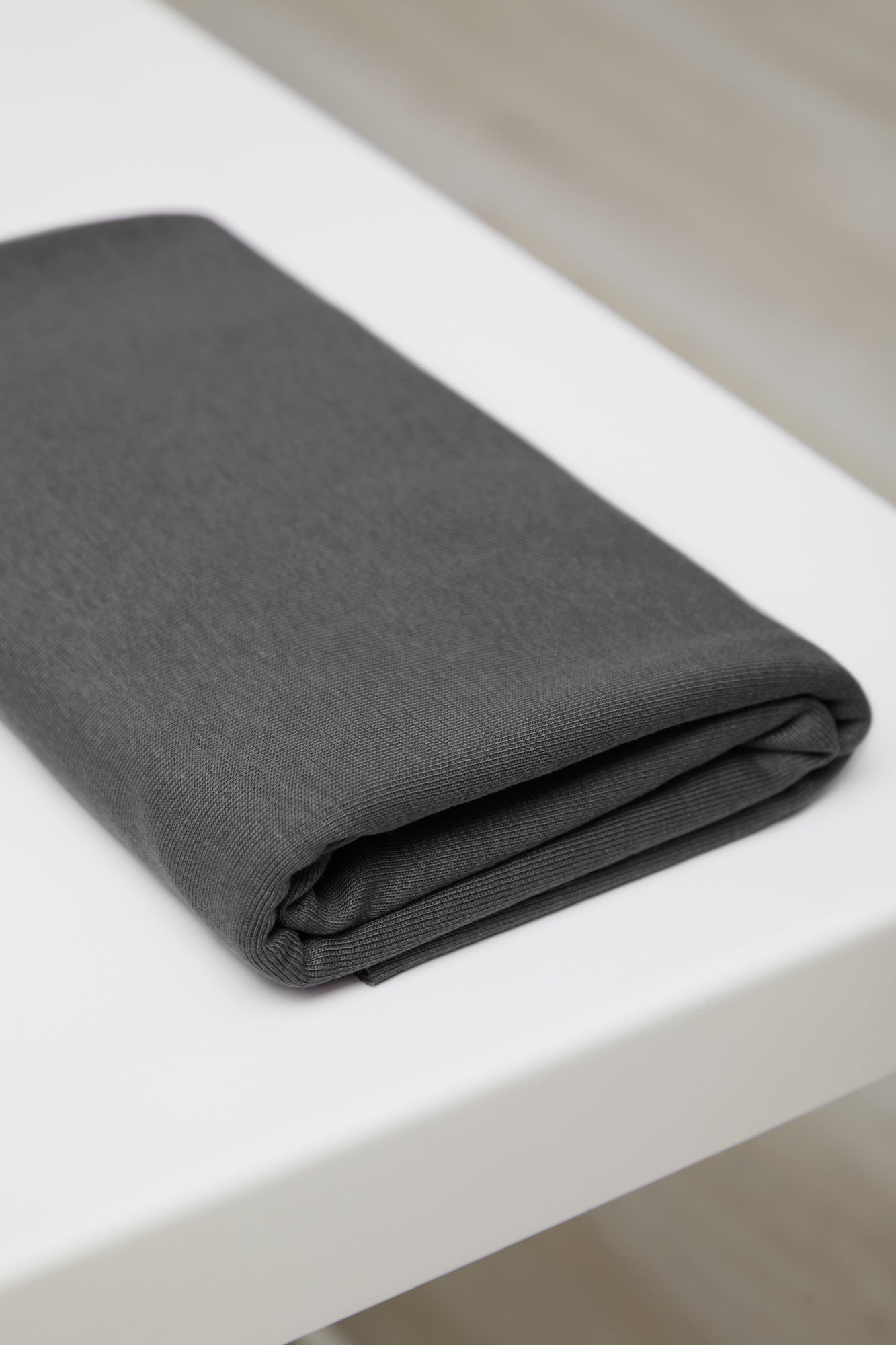 Dark grey organic cotton and tencel jersey knit sewing fabric folded on white table