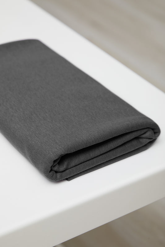 Dark grey organic cotton and tencel jersey knit sewing fabric folded on white table