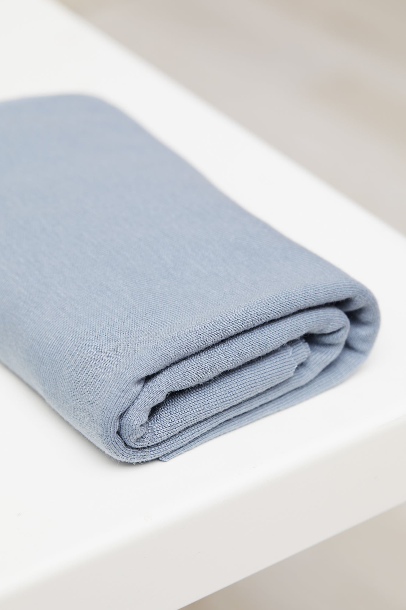 Sky blue organic cotton and tencel jersey sewing fabric folded on white table