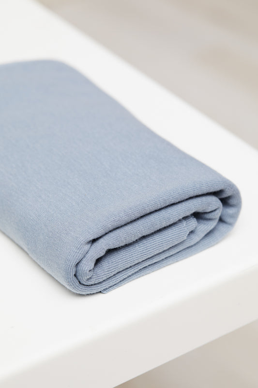 Sky blue organic cotton and tencel jersey sewing fabric folded on white table