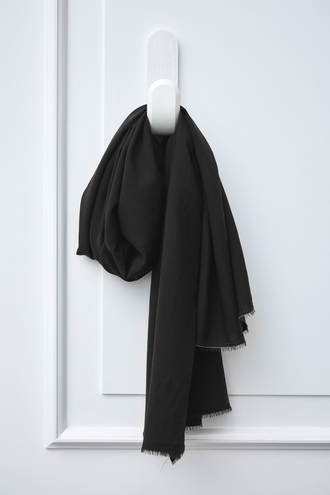 Piece of black Vida voile tencel sewing fabric handing on white hook