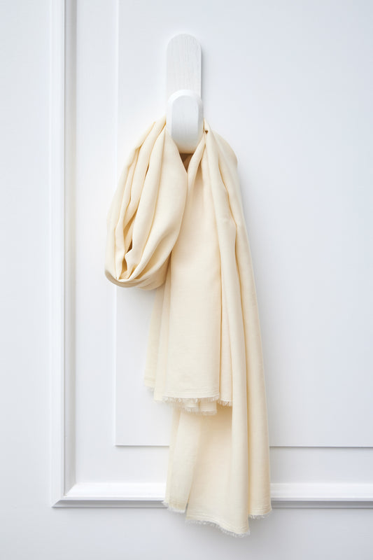 Piece of Vida voile tencel sewing fabric in colour shell (cream) hanging on white hook
