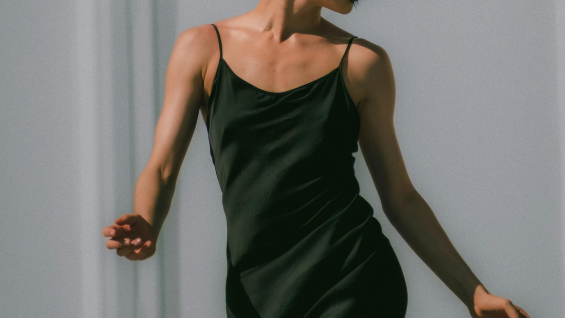 woman moving in deep green silk bias dress against a white background
