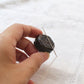 Hand holding dark grey ceramic needle rest by cohana with needle lying on top