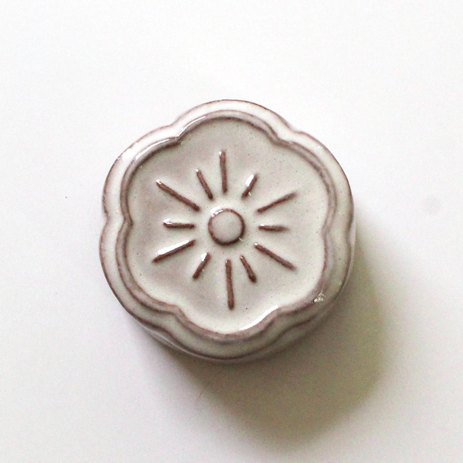 Close up of cohana flower shaped ceramic magnetic needle rest in white