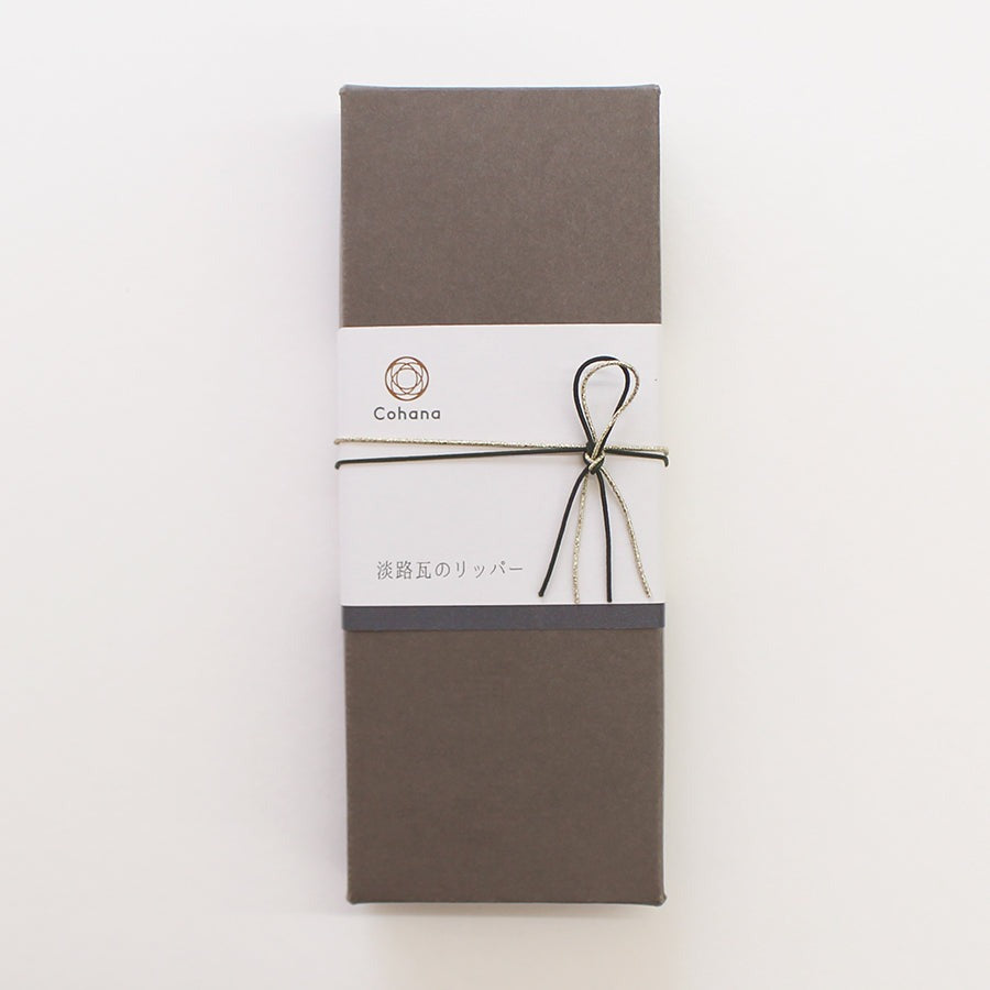 Dark grey box with cohana branded logo and threads tied around it