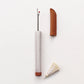 White ceramic handled seam ripper by Cohana with white tassel and brown leather protector case