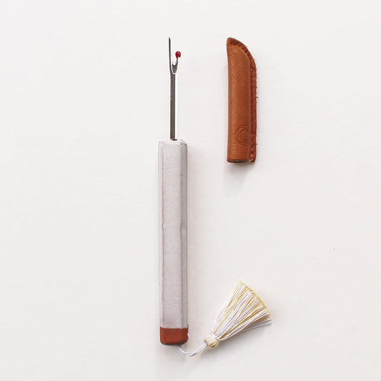 White ceramic handled seam ripper by Cohana with white tassel and brown leather protector case