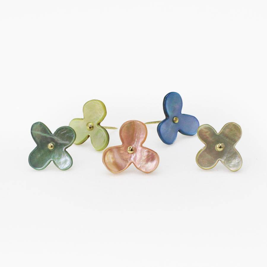 Collection of flower shell push pins in pastel colours against white background