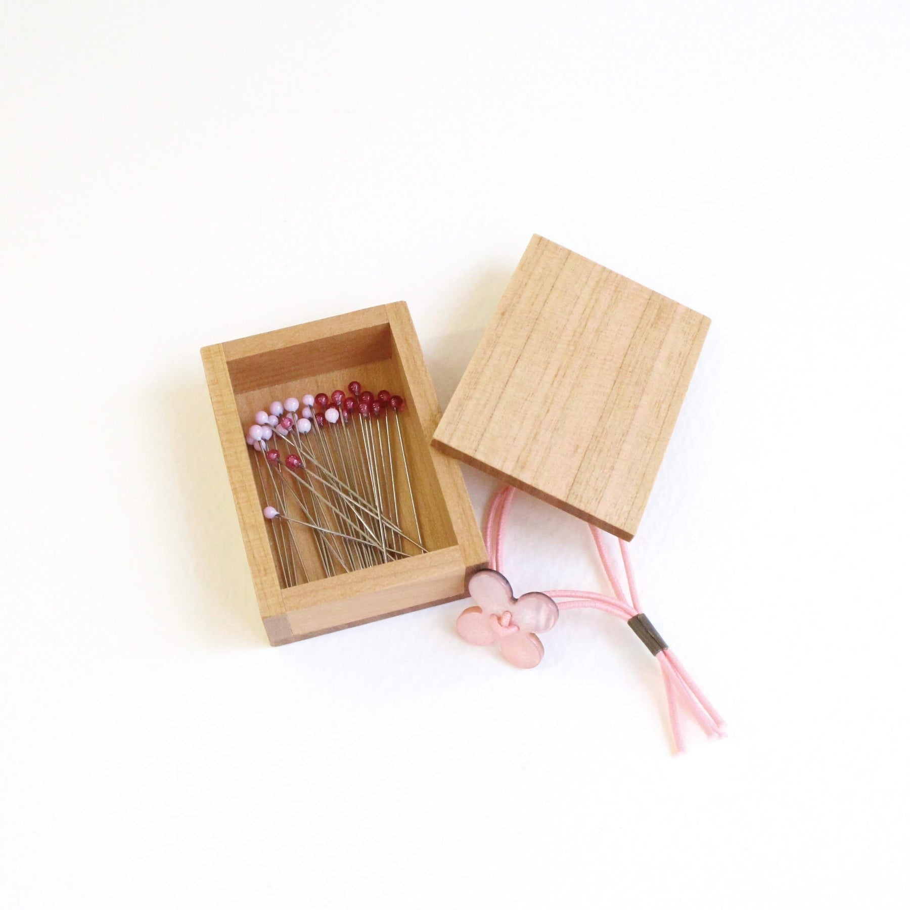 Pink cohana glass headed pins in wooden storage box