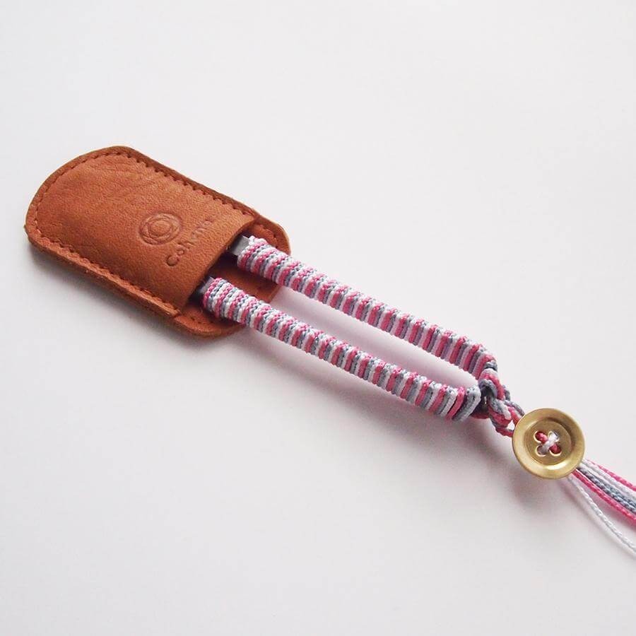 Thread snips with pink and grey thread wrapped handles and brown leather tip protector