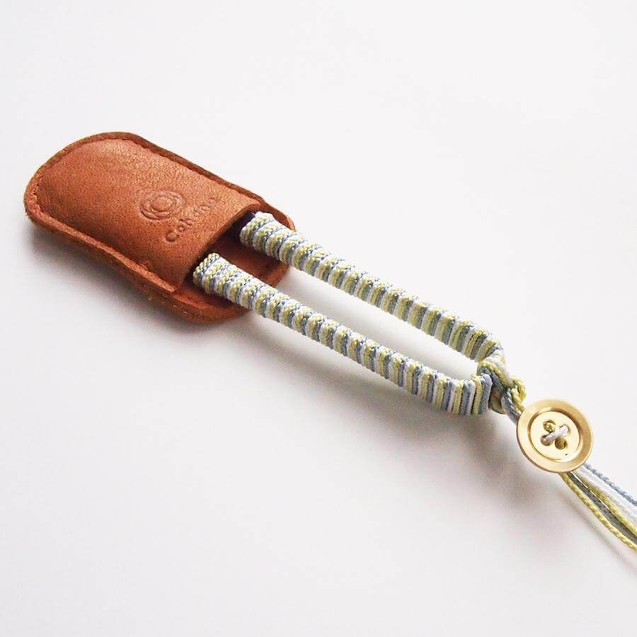 Cohana thread snips with yellow and grey thread wrapped handles sitting in leather protector case