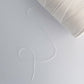 Close up photo of cone of tencel sewing thread in natural on white background