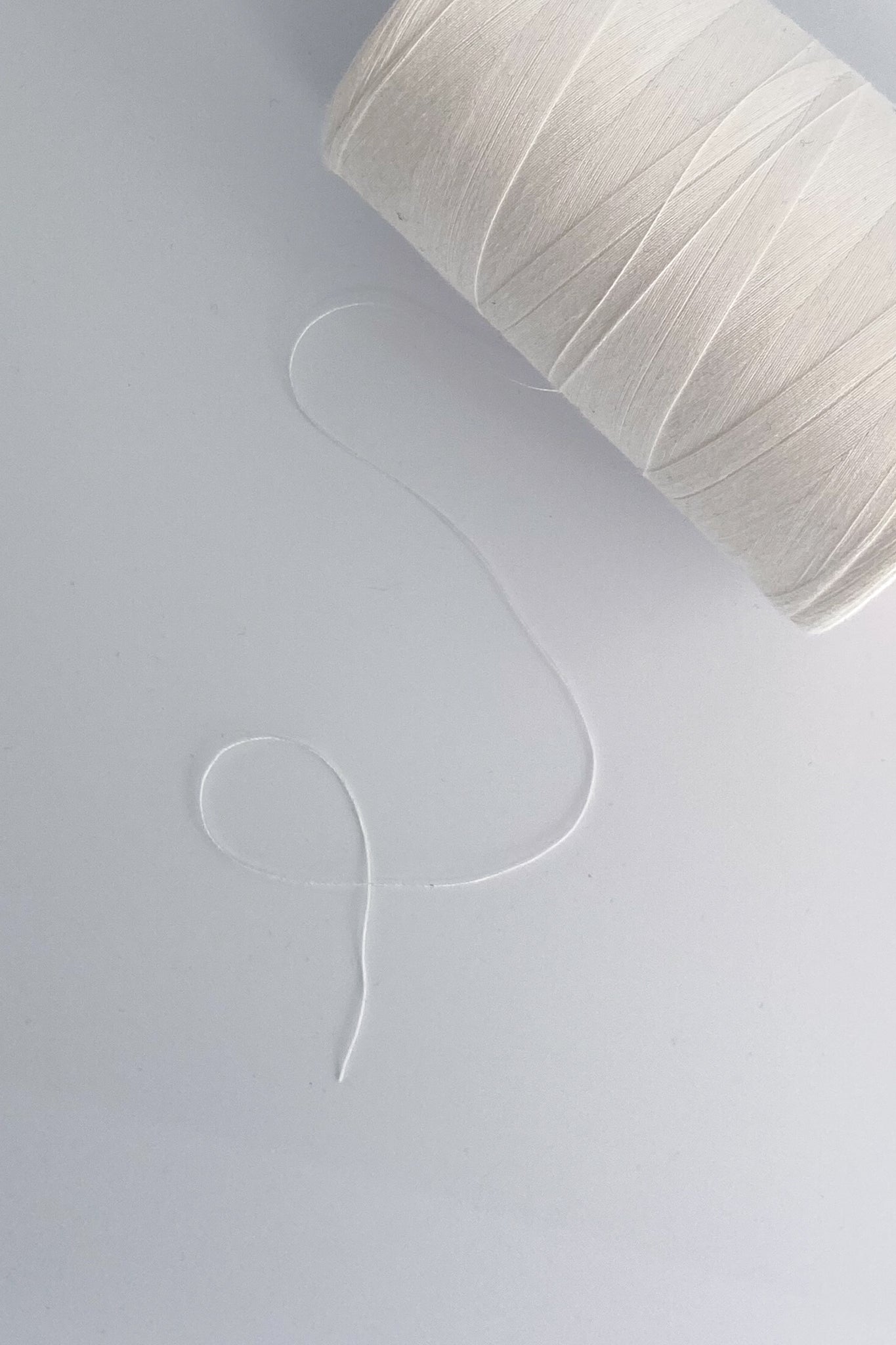 Close up photo of cone of tencel sewing thread in natural on white background