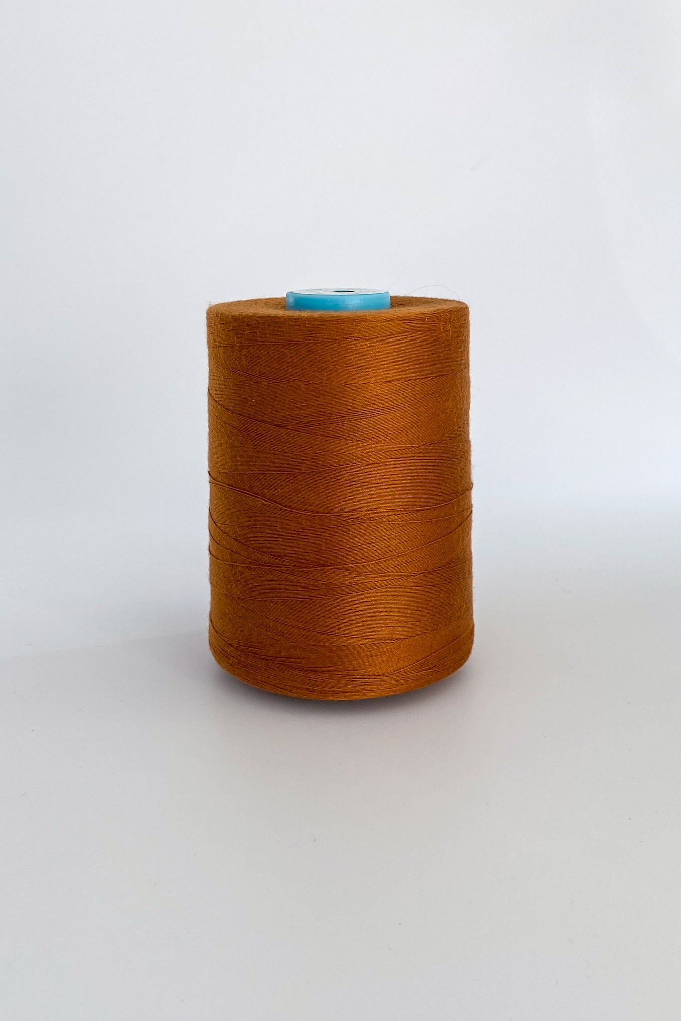 Spool of crafil tencel sewing thread in bronze on white background