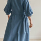 Back view of person wearing a blue Amalie wrap dress with puffed sleeves against a plain background.