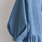 Close up of puffed sleeve of blue dress on a plain background
