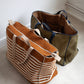 Two tote bags, one brown with closed zipper and white stripes, and one green, on a light floor.