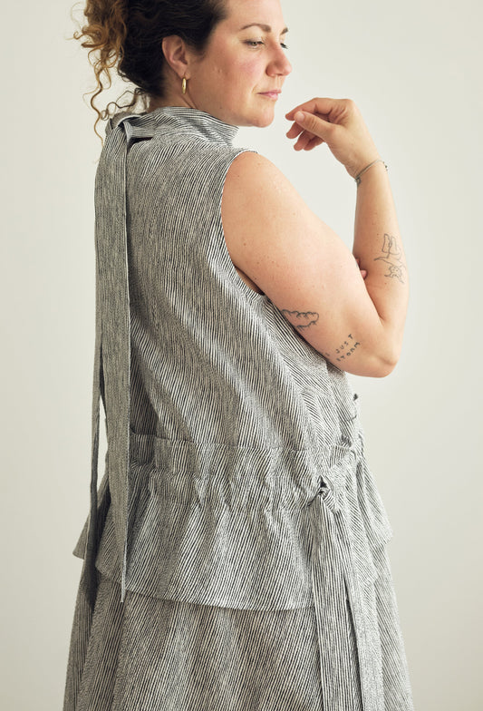 Woman wearing a sleeveless striped dress against a plain background