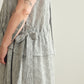 Close up of a person wearing a grey and white striped dress with a white background.