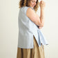 Woman wearing a light blue sleeveless Paloma top and beige skirt against a plain background