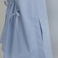 Close-up of a light blue Paloma top, showing side slit detail and matching drawstring tie on a plain light gray background.