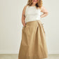 Woman wearing a beige skirt and white top against a plain background