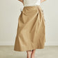 Person wearing a beige skirt and a white top on a plain background