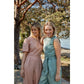 Two white women standing next to each other smiling wearing pastel coloured jumpsuits in the sunshine
