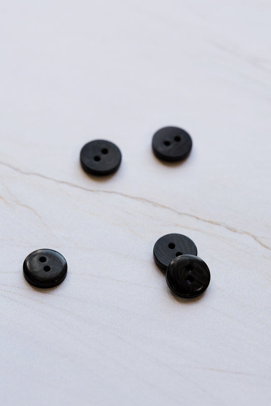 Collection of 11mm black 2-hole corozo  shirt buttons on a white background