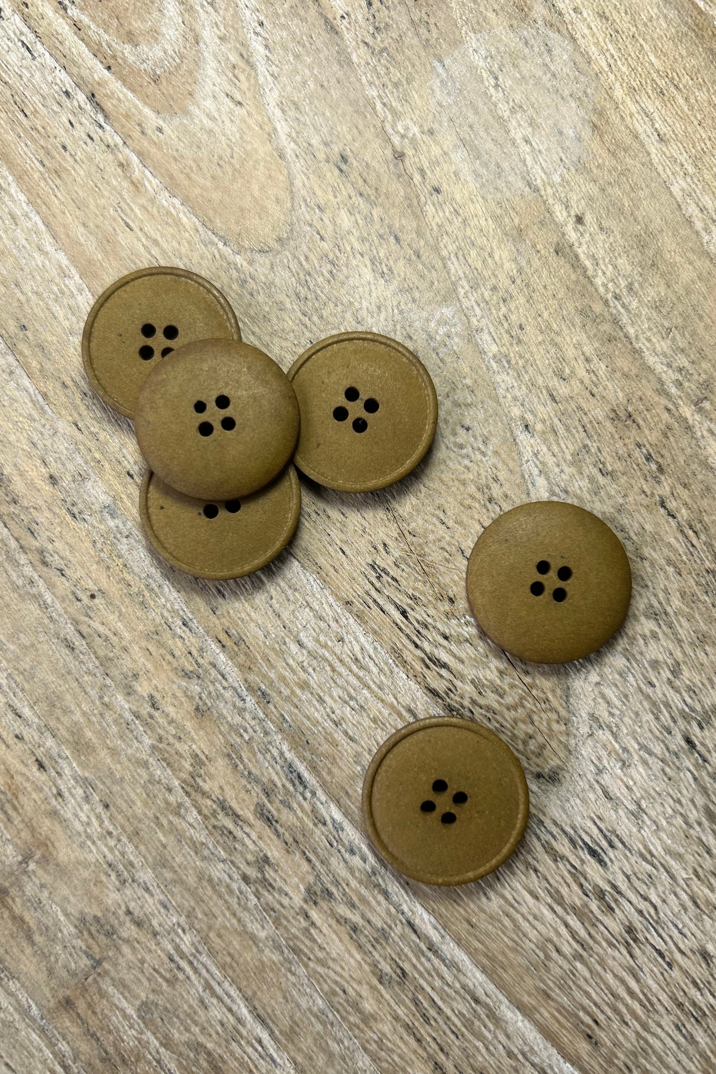 Collection of merchant and mills 20mm buttons in tan colour on wood background