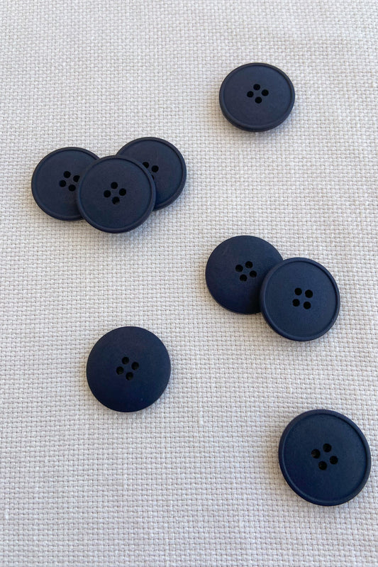 Collection of 20mm black hemp buttons on white cloth