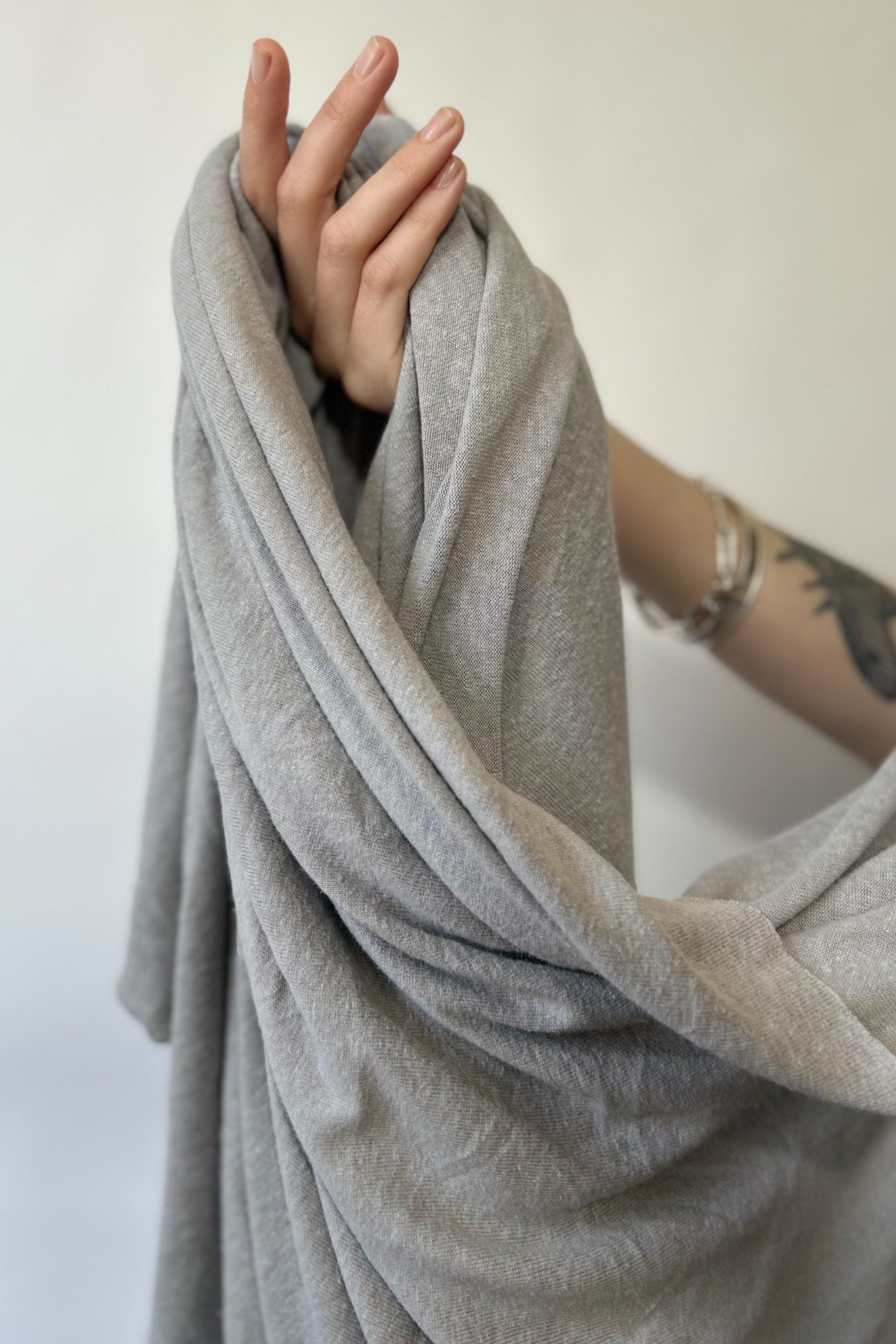 Hand holding grey hemp and lyocell jersey knit fabric