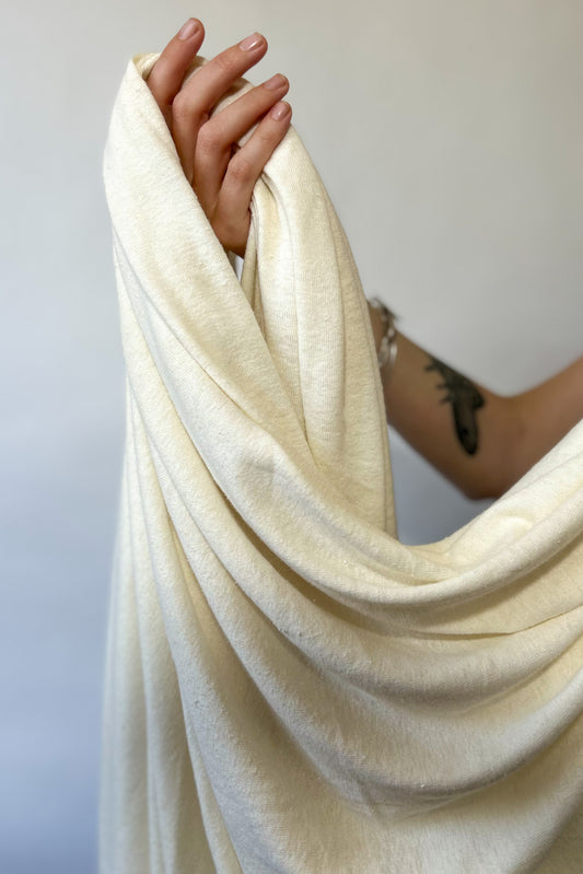 Hand holding cream coloured hemp and lyocell jersey knit fabric
