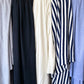 Row of hemp jersey fabrics hanging over rail in grey, black, natural white, navy and white stripe and periwinkle blue