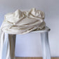 Cream coloured hemp and lyocell jersey knit fabric piled on white stool