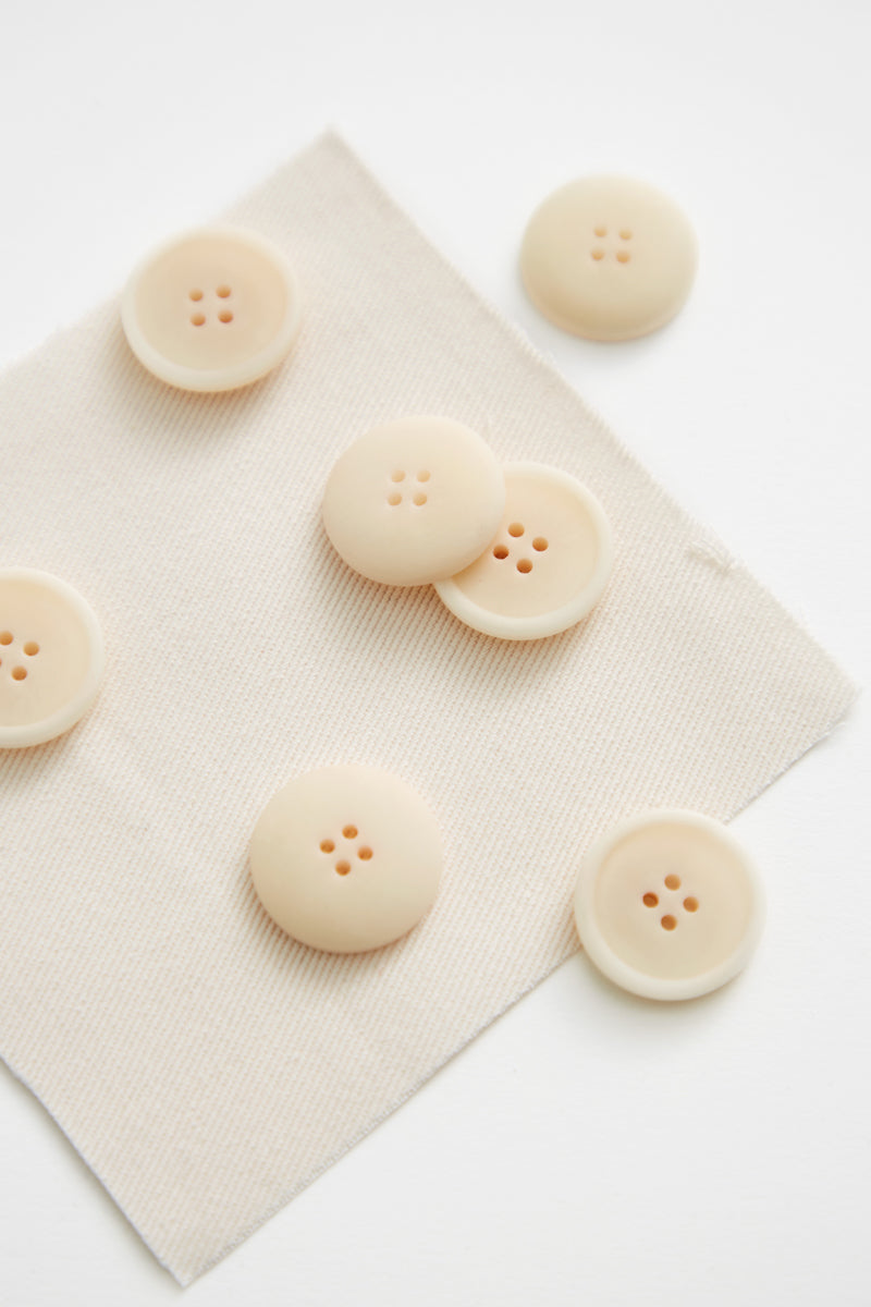 Close up of creamy white corozo sewing buttons on matching fabric swatch