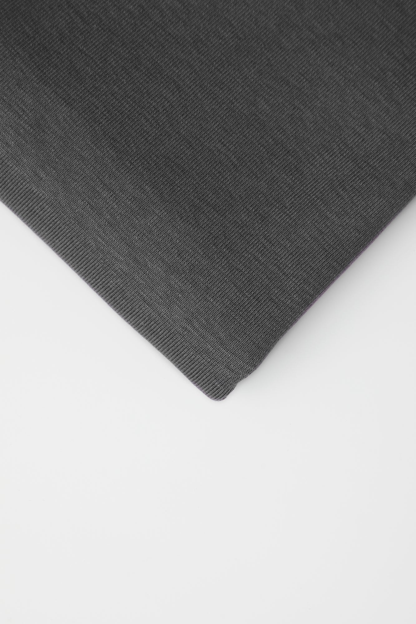 Close up of dark grey organic cotton and tencel knit sewing fabric on white background