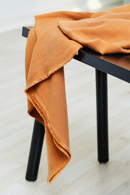 Mara linen blend tencel sewing fabric in colour mustard, draped over stool