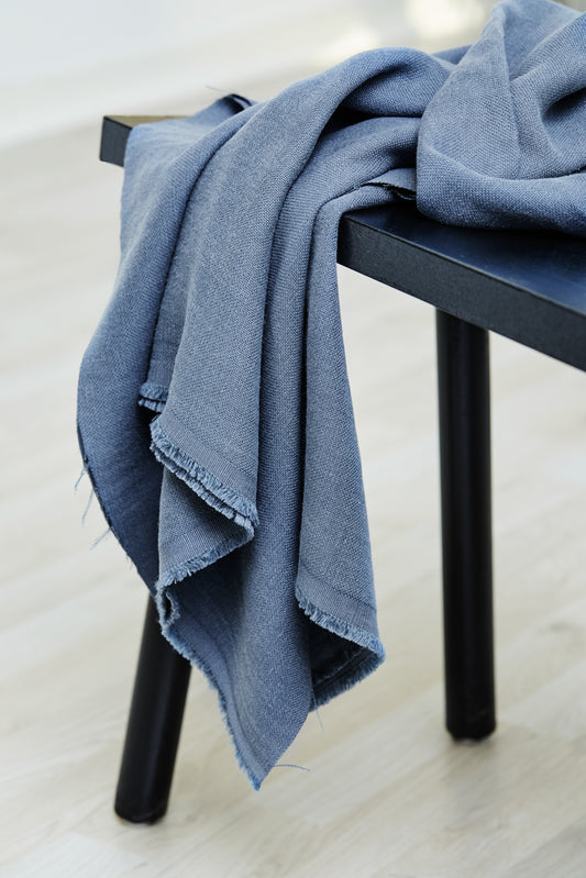 Mara linen blend tencel sewing fabric in dusty blue, draped over stool