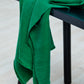 Mara linen blend tencel sewing fabric in colour frog green, draped over stool